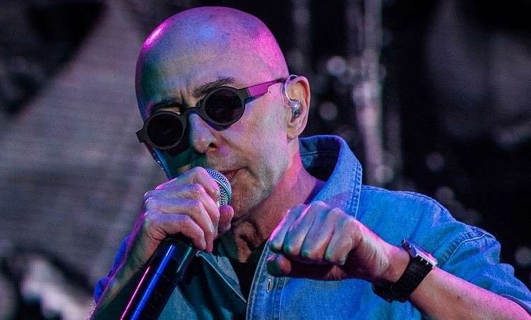  El Indio Solari cantando en un concierto, con gafas de sol y chaqueta de jean.