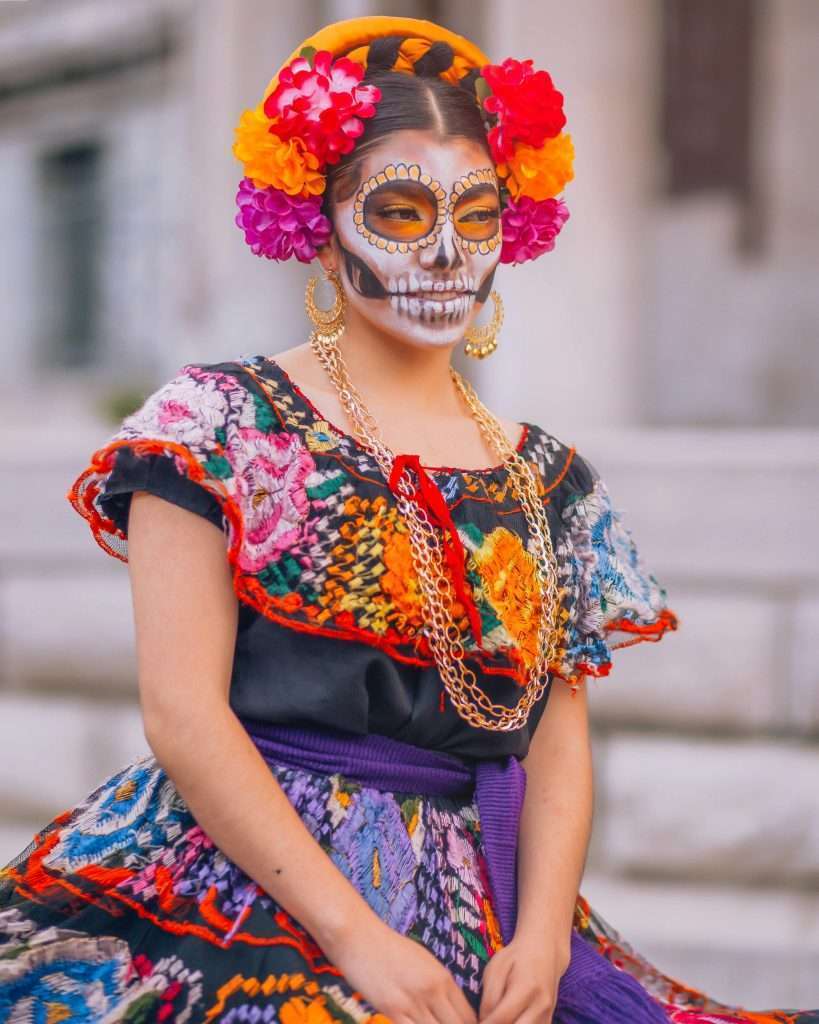 Mujer con maquillaje de Catrina y vestido tradicional.
